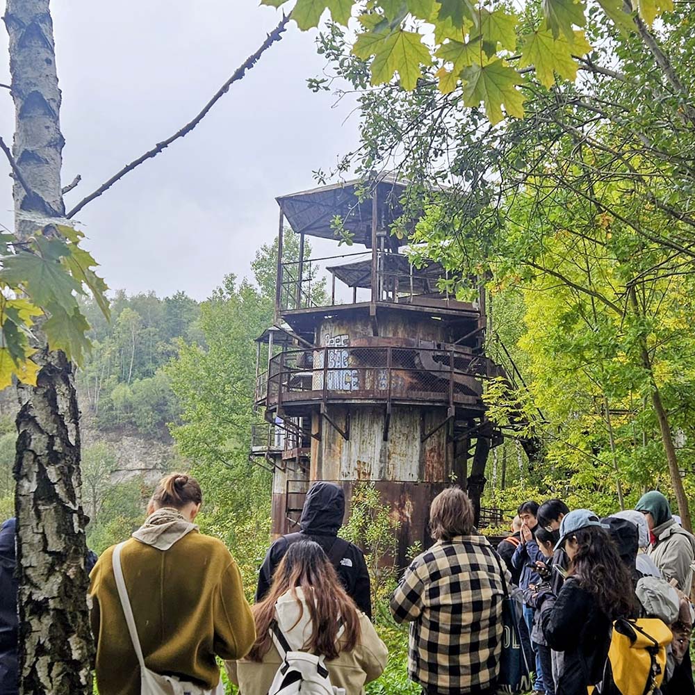 A group of students in Liban Quarry sketching and taking notes about the rusted, disused, lime kilns and hoppers, industrial remnants from the post-war quarry operations.