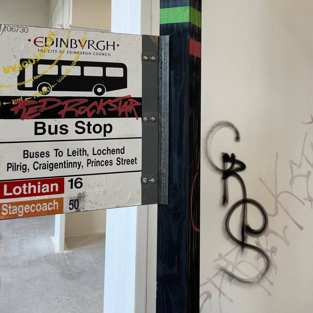 Graffitied bus stop sign.