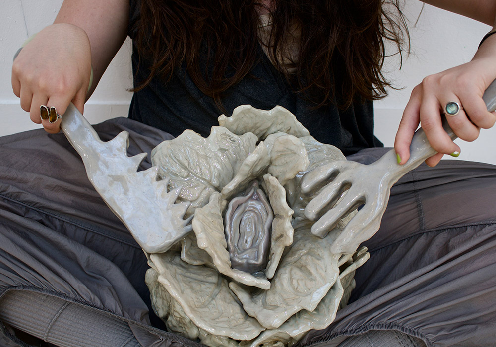 A person using a large knife and fork to eat a cabbage with a vulva