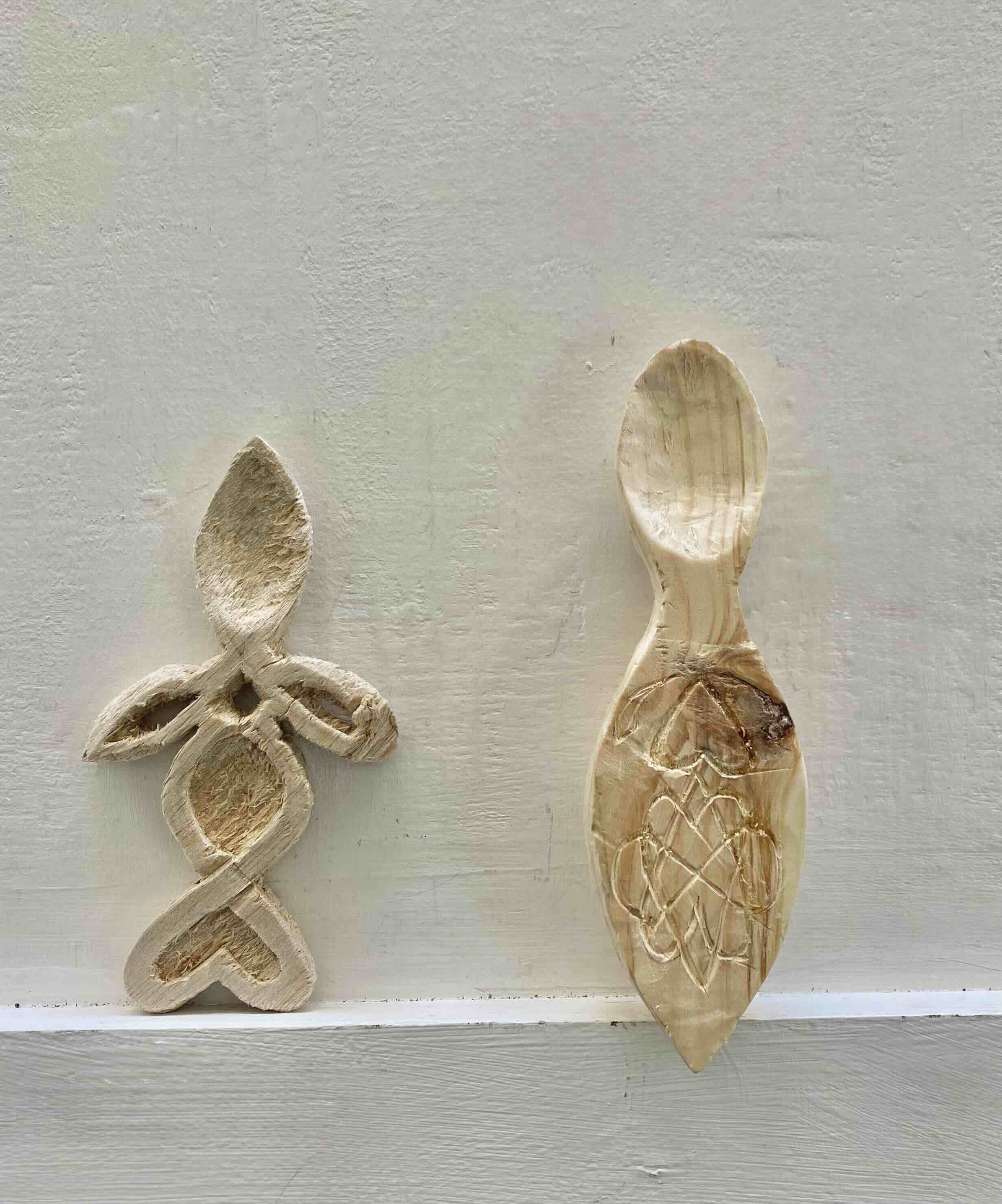 two hand carved wooden spoons sat on a plinth