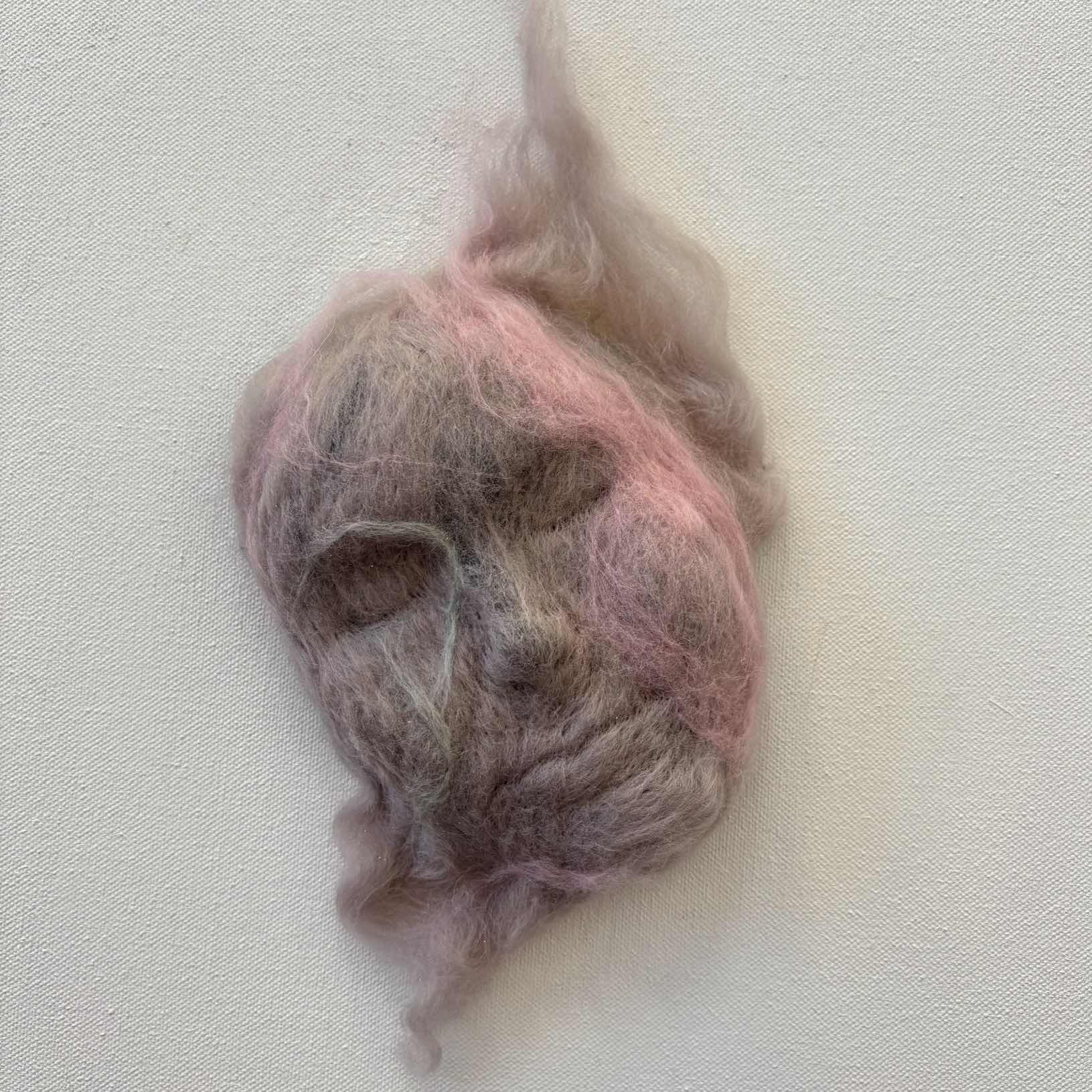 Needle felt sculpture of a sleeping face in purple, pink and green 