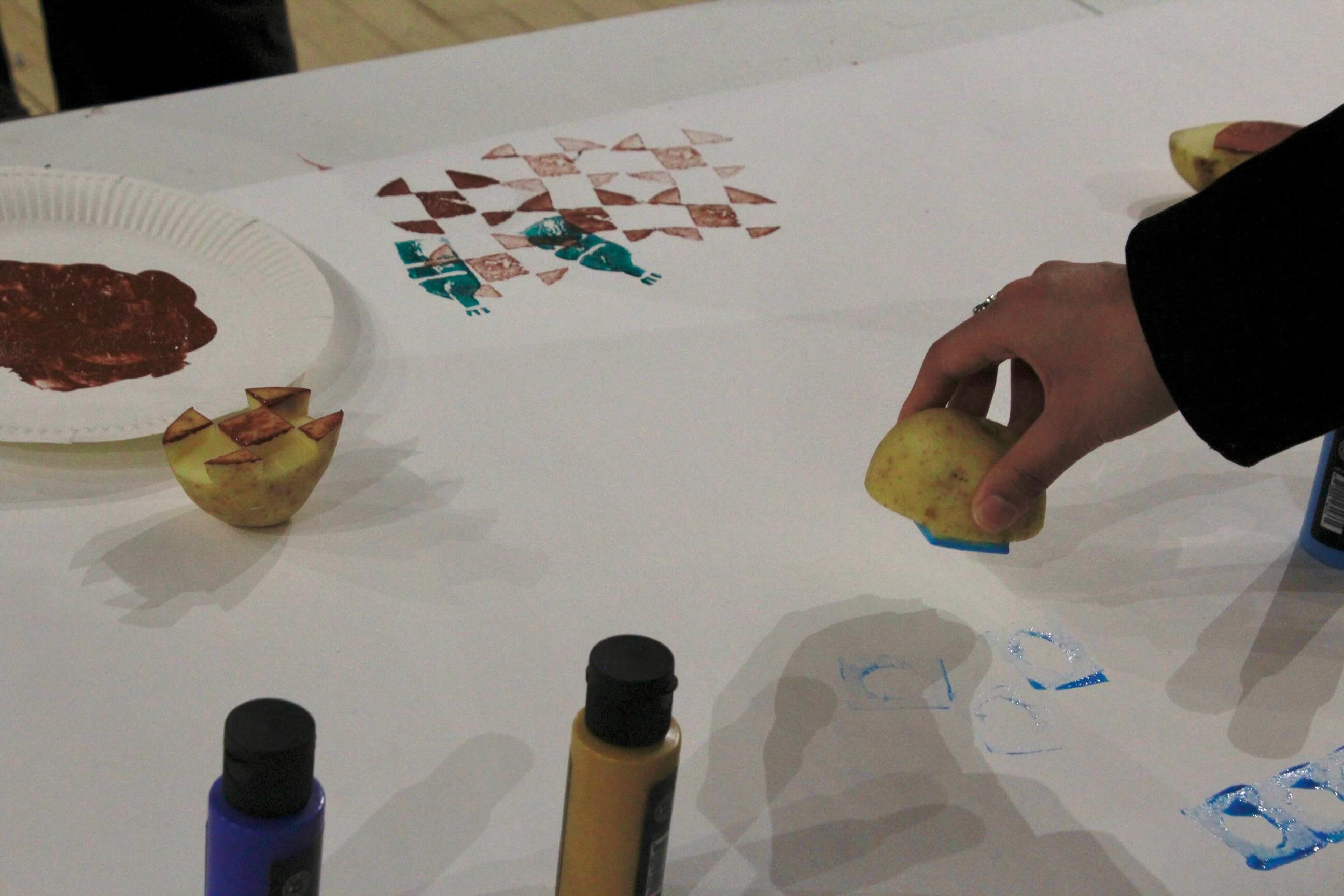 A close up photo of a hand holding a potato about to print 