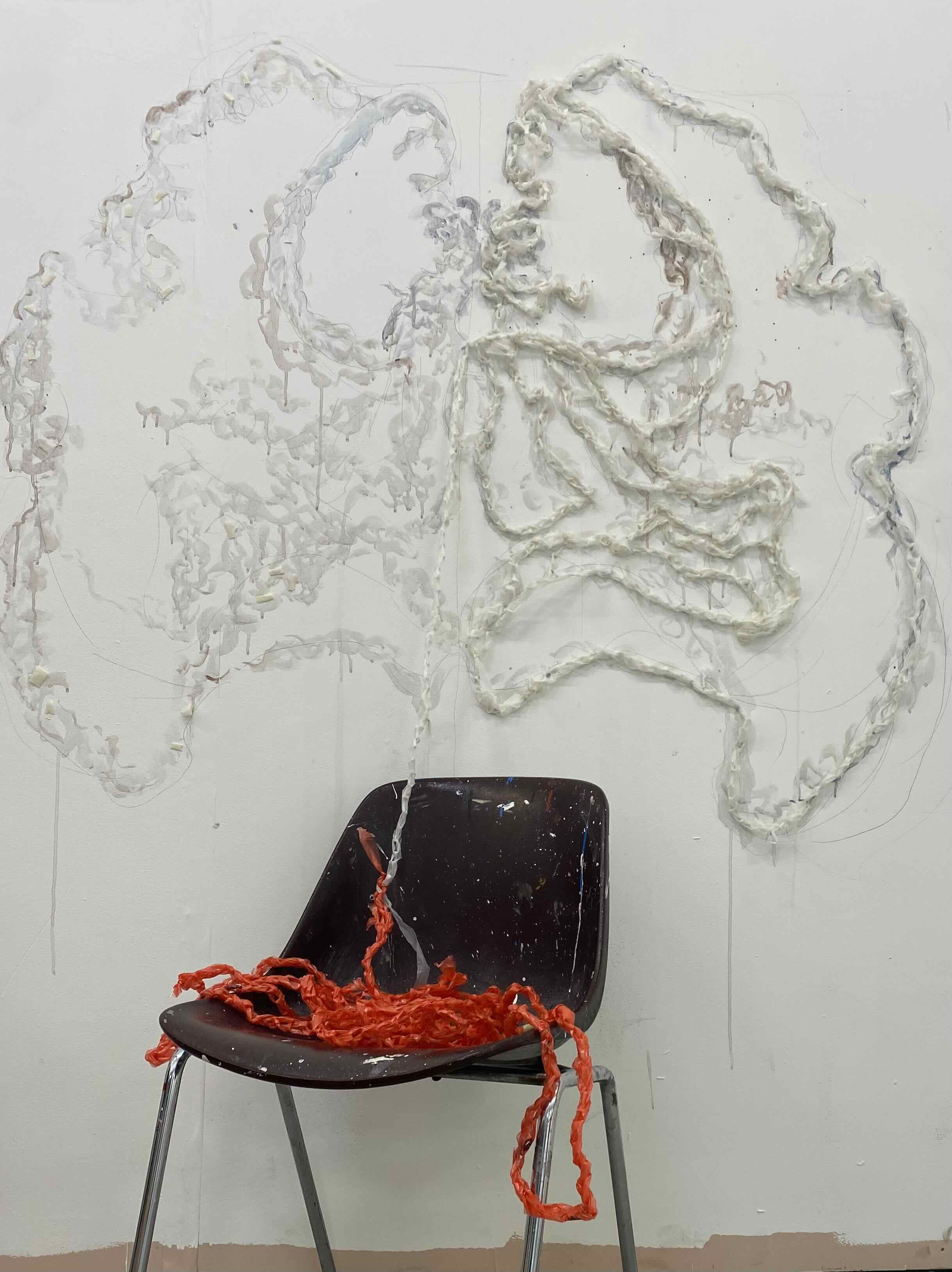 Crochet plastic bags hung in a pelvis symbol and trailing onto a chair with crochet hook at the end