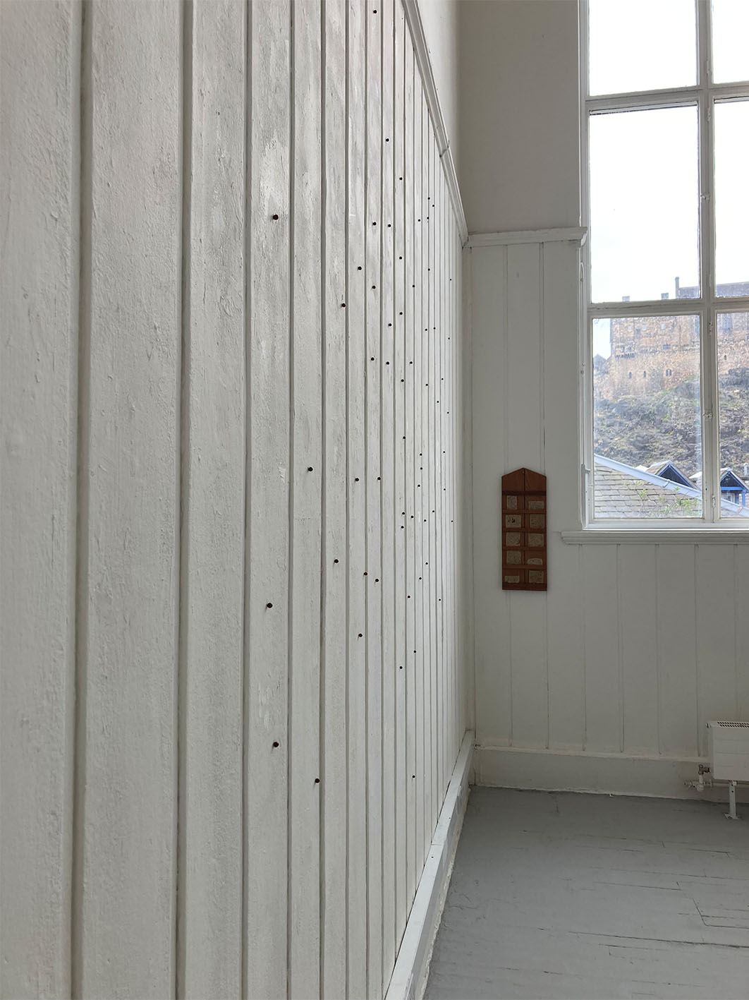 Image of beads installed spread across a wall, with oak hymn board also on the wall. 