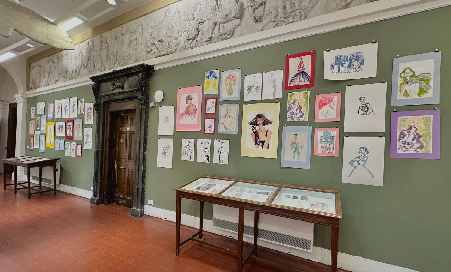 drawings displayed on a green wall in the ECA