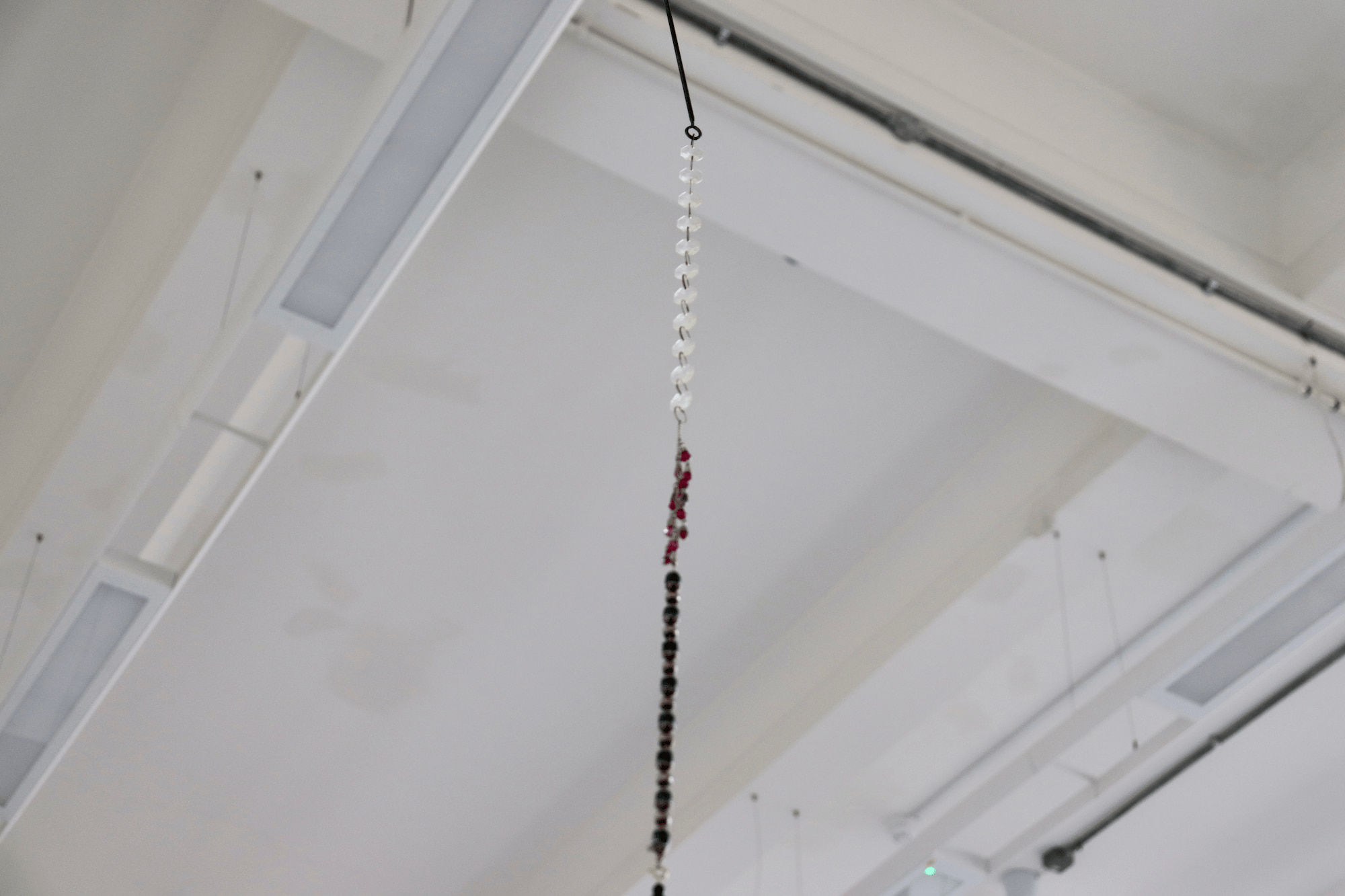 a beaded sculpture hanging from an iron rod at the top of the wall