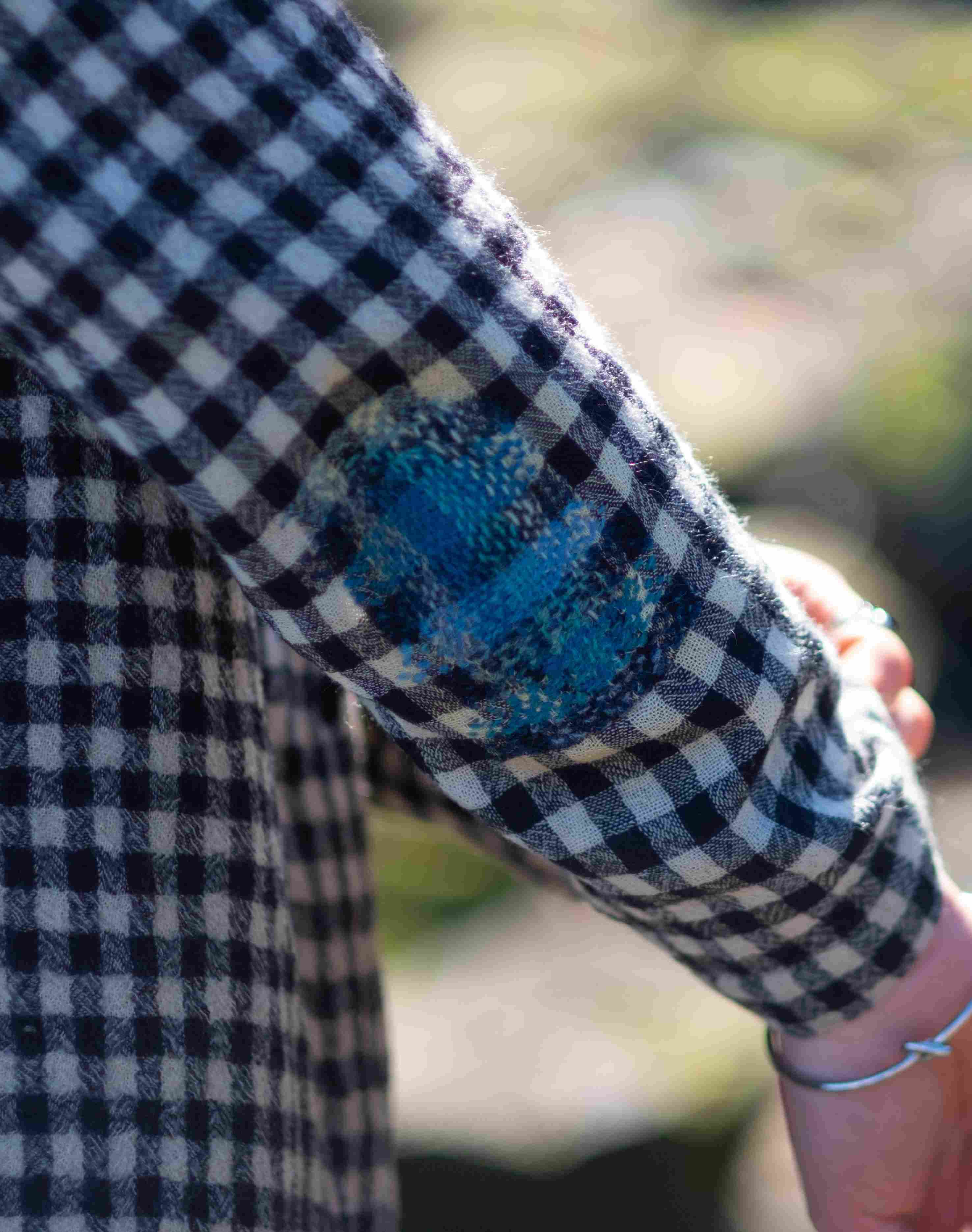 Darning from mending workshop. Blue repair on a checkered shirt.