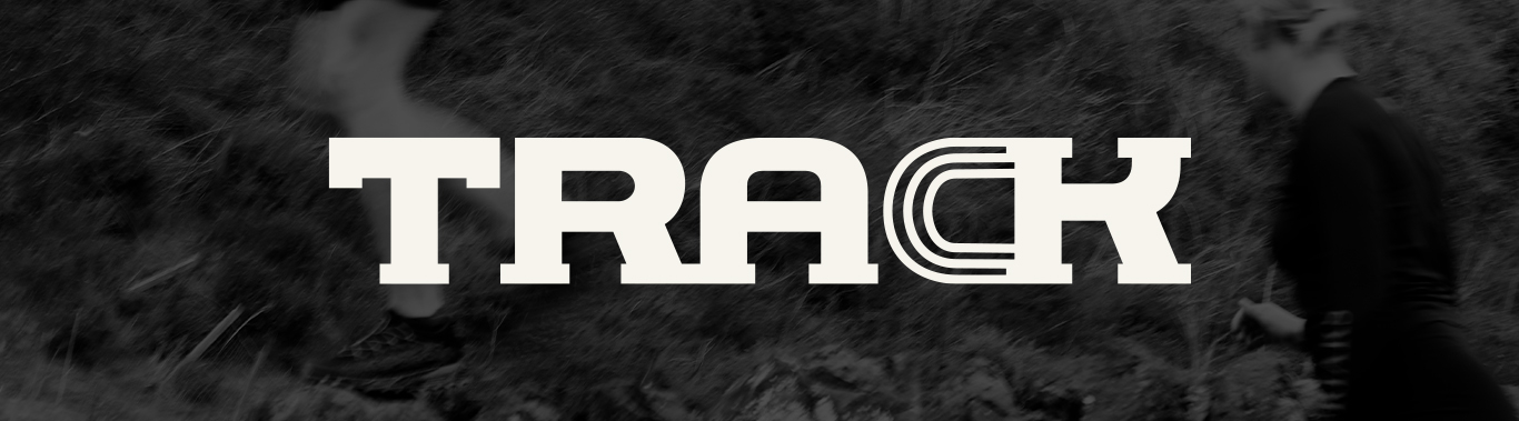 TRACK logo in bold white lettering over a blurred black and white photograph of two runners moving through an outdoor trail landscape. The logo is centred across the image, with the ‘C’ formed from layered track inspired curved lines.