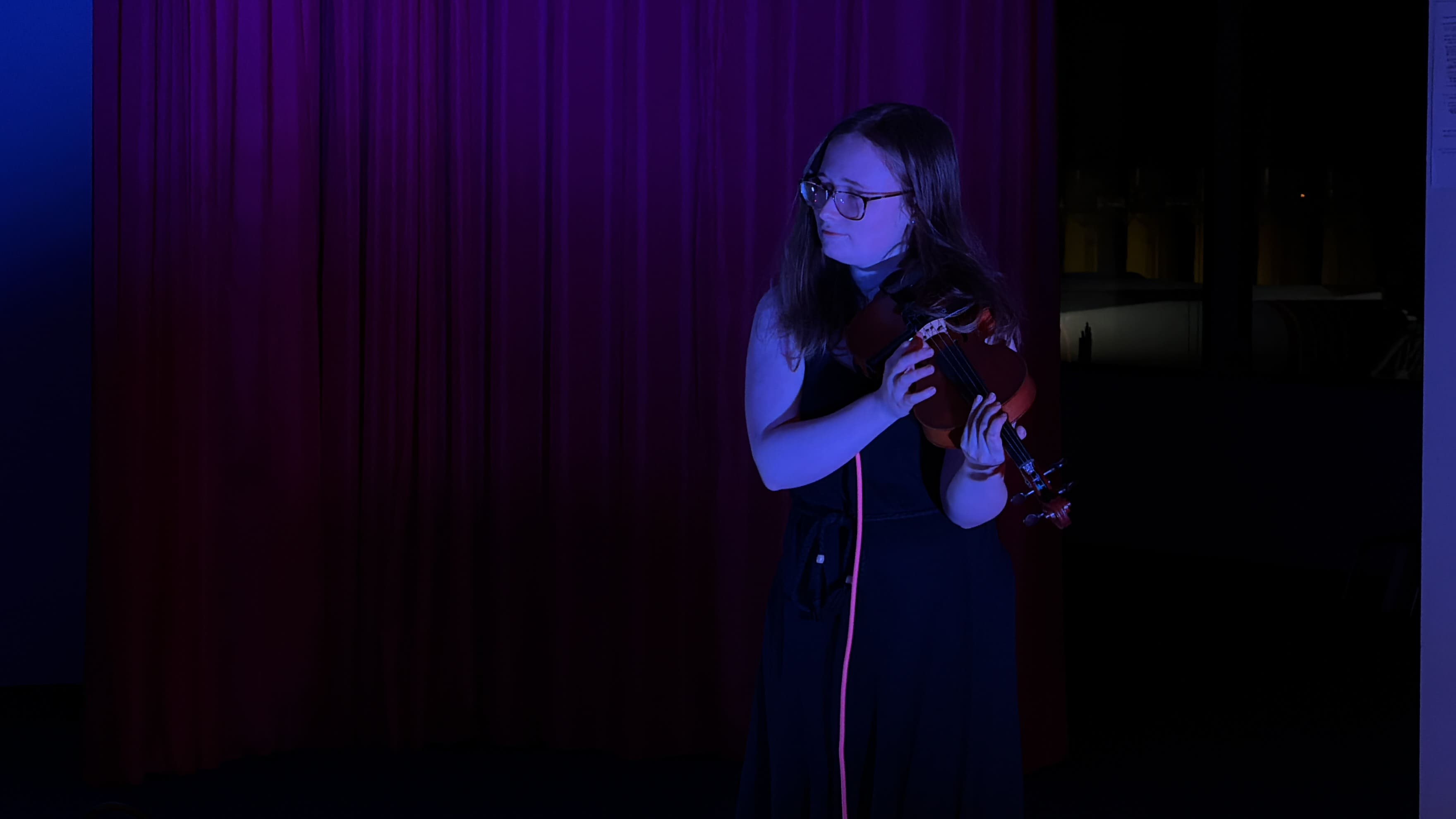 A photo of Ailsa playing violin in a ‘Raging Orchestra’ performance - a collaboration for Composers Orchestra, with Selenay Tektunali and Roos Walkers