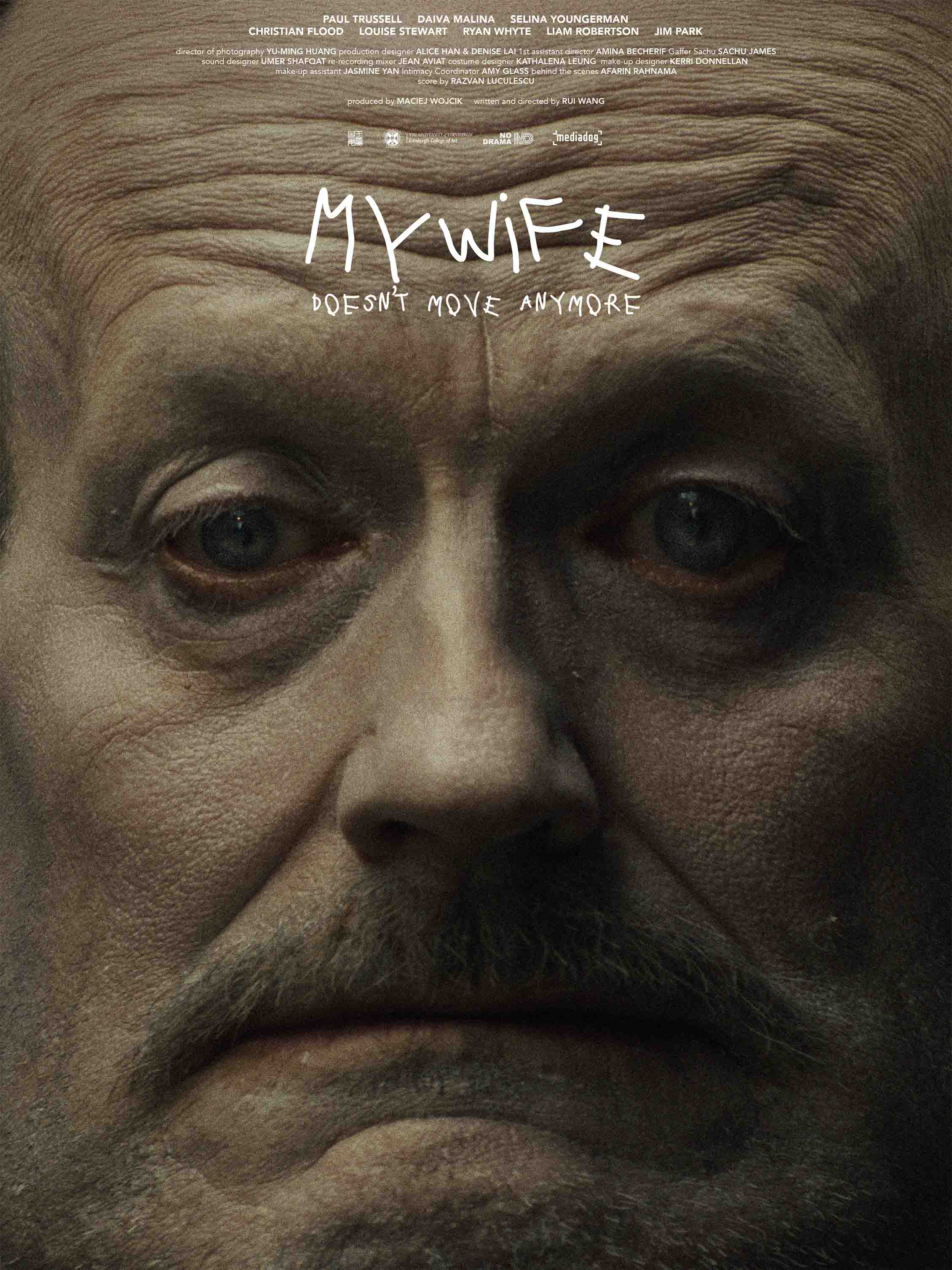 Close-up film poster of a middle-aged man’s face with tired eyes and a moustache, staring directly at the viewer, with the handwritten title “My Wife Doesn’t Move Anymore” overlaid above.
